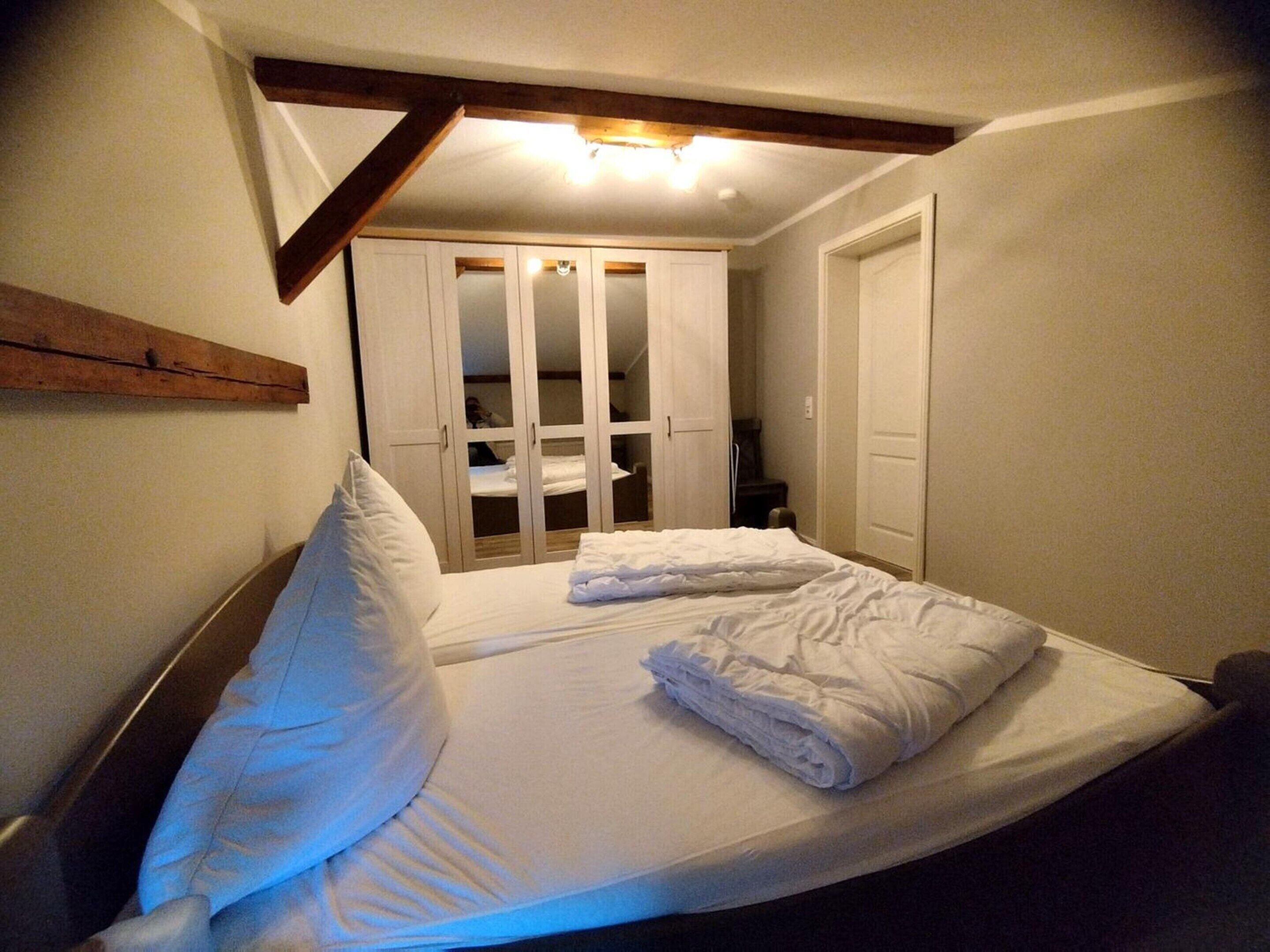 Een slaapkamer met een bed, een kledingkast en een deur.