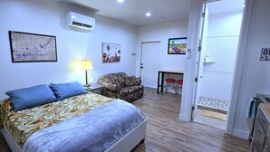A hotel room with a bed, a chair, a desk, and a door with a sign. - Private, Modern Casita, Coffee Bar, Wet Bar (Page)