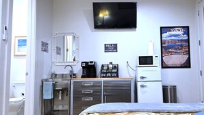 A compact hotel room with a kitchenette, a TV, a poster of Lake Powell, and a door to the outside. - Private, Modern Casita, Coffee Bar, Wet Bar (Page)