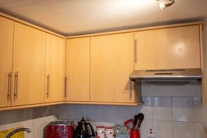 A kitchen with wooden cabinets, a stove, and various kitchen utensils.