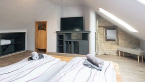 Una camera da letto moderna con soffitto a volta, una televisione, una parete in pietra e una panca.