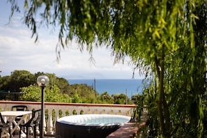 Une terrasse avec une table et des chaises, une lampe et une vue sur la mer.