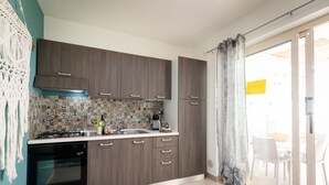 Een keuken met donkerhouten kastjes, een decoratieve spatwand, een gasfornuis en een schuifdeur naar een buitenruimte.