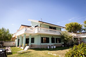 Une maison à deux étages dotée d’un balcon, d’une pelouse et de mobilier d’extérieur.