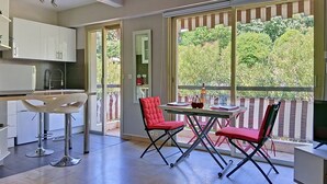 Una cocina moderna con armarios blancos, un taburete de bar y un comedor con sillas rojas y una mesa.