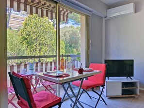Ein Balkon mit Esstisch, Fernseher und einem roten Sessel.