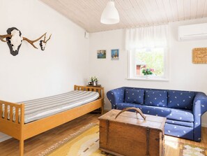 Et værelse med en træseng, en blå sofa, et træskrin og et vægmonteret kranie.