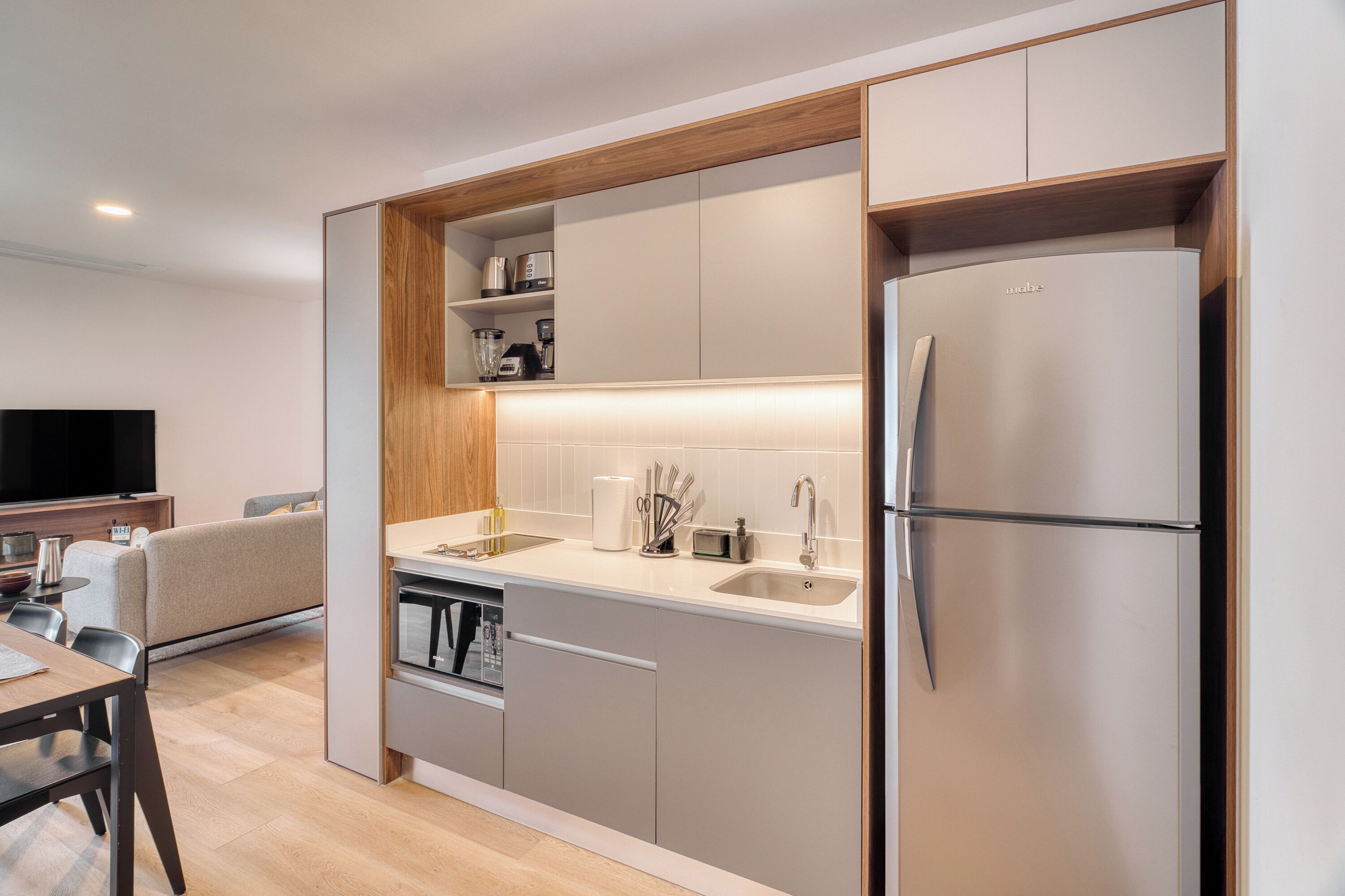 A modern kitchen with built-in appliances, a dining area with a table and chairs, and a flat-screen TV.