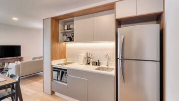 A modern kitchen with built-in appliances, a dining area with a table and chairs, and a flat-screen TV.