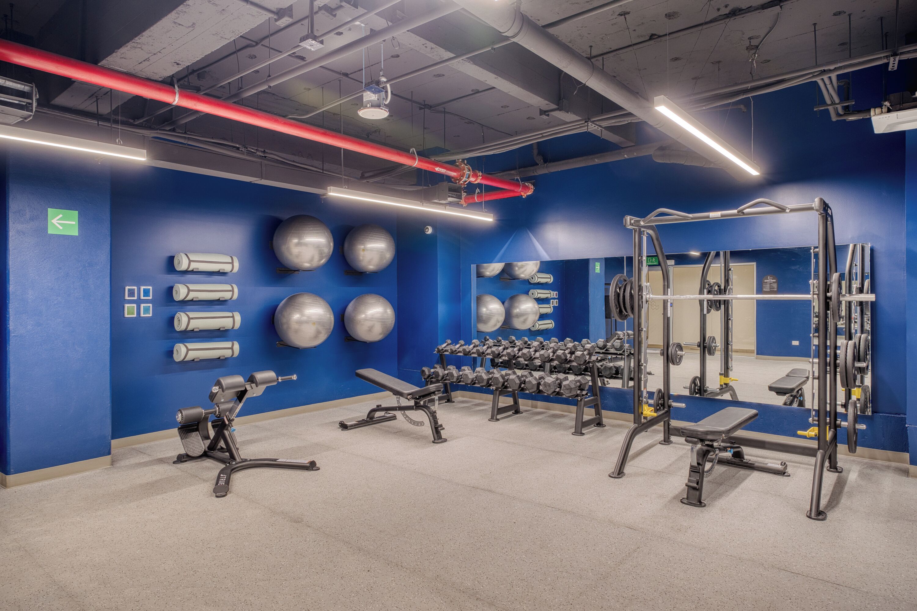 A gym with exercise equipment, a blue wall, and a mirror.