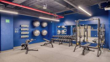 A gym with exercise equipment, a blue wall, and a mirror.