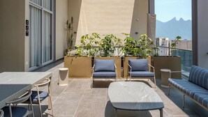 Ein Balkon mit Tisch, Stühlen, einer Couch und Topfpflanzen.