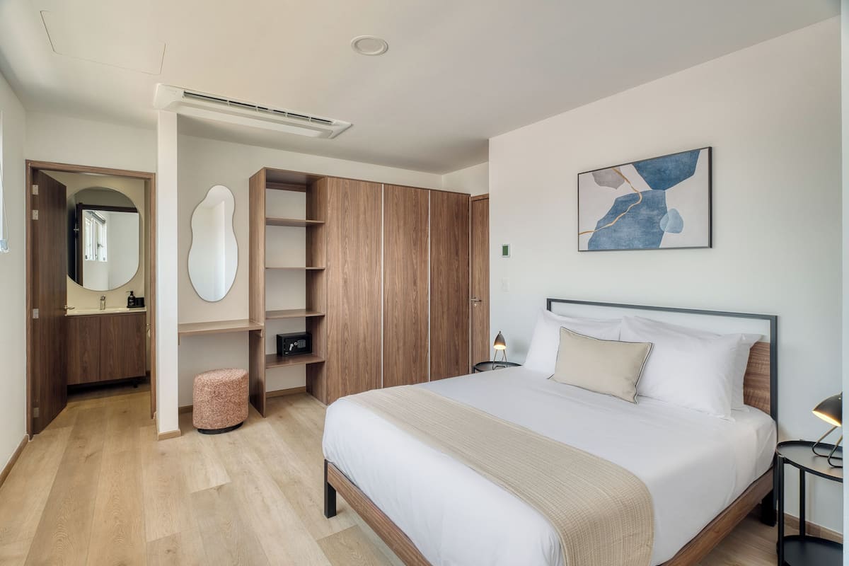 Un dormitorio moderno con una cama grande, un armario de madera y un espejo.