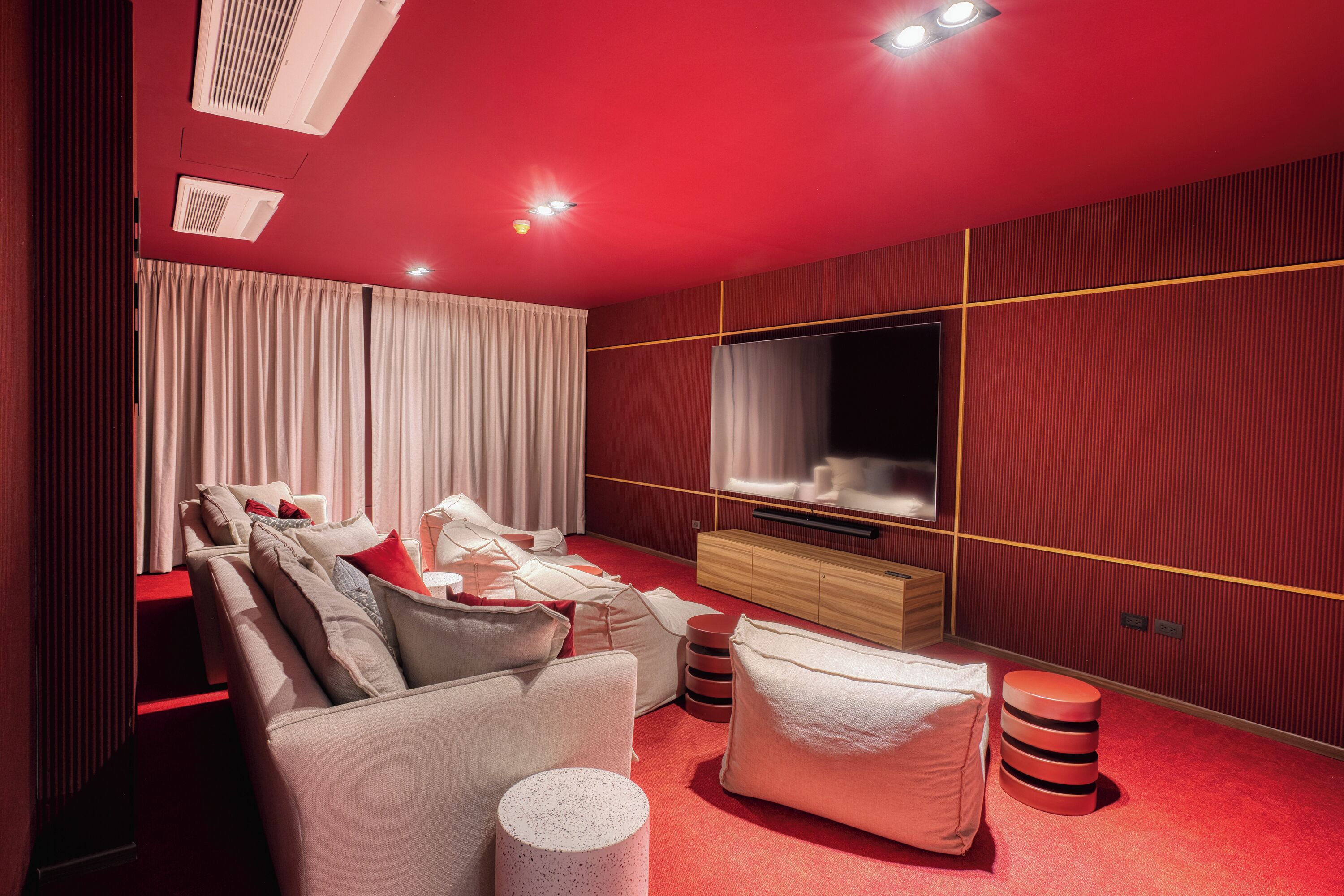A modern living room with a red carpet, a sofa set, a TV, and a wooden cabinet.