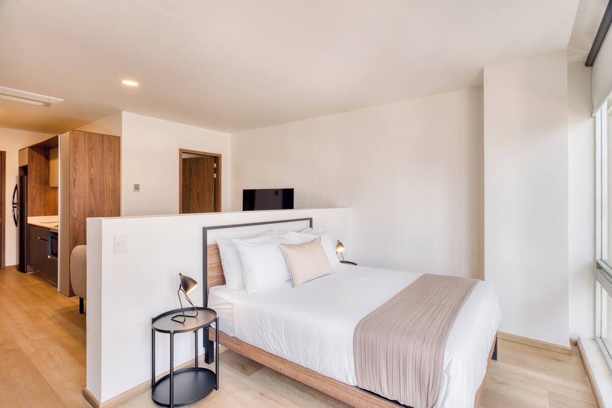 Un dormitorio moderno con cama, mesita de noche y televisor.