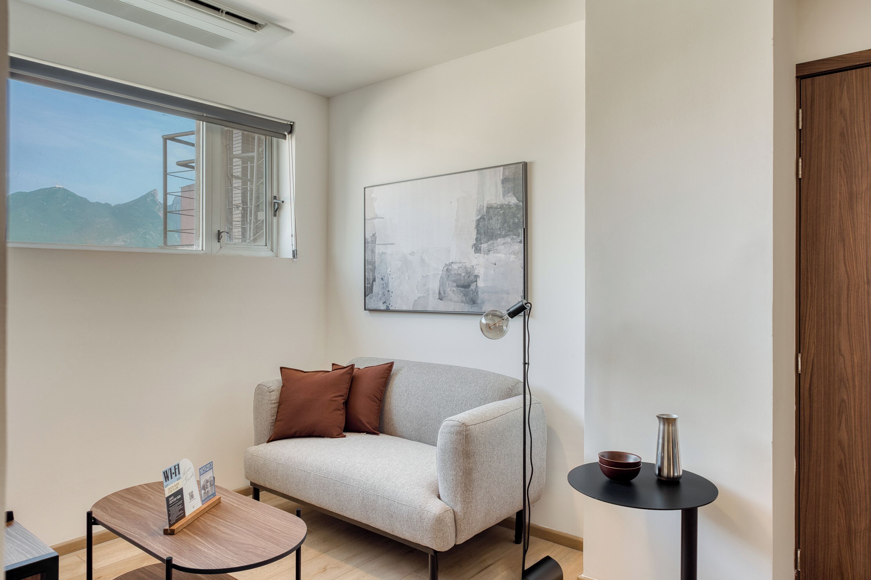 A modern room with a sofa, a small table, a floor lamp, and a painting on the wall.