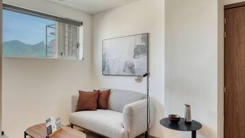 A modern room with a sofa, a small table, a floor lamp, and a painting on the wall.