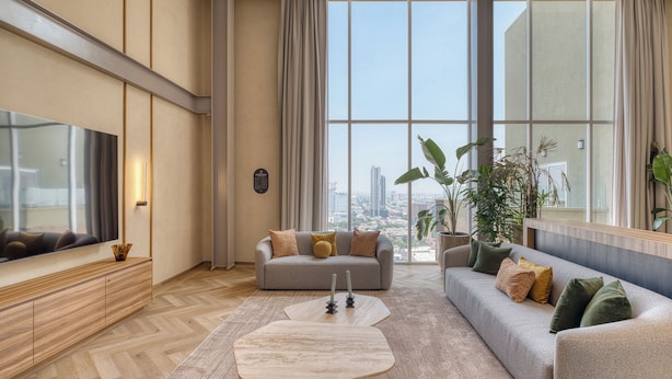 Ein modernes Wohnzimmer mit großem Fenster, einer Couch, einem Couchtisch und einem Fernseher.