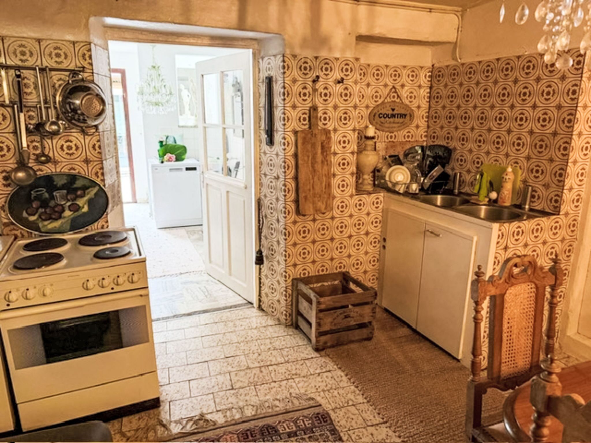 A kitchen with patterned tiles, a stove, a sink, and a wooden crate.