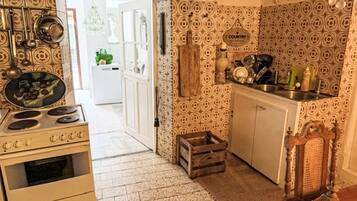 A kitchen with patterned tiles, a stove, a sink, and a wooden crate.