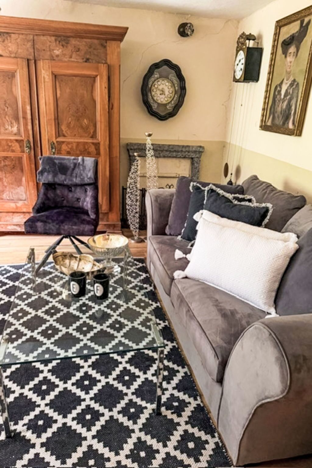Una sala de estar con sofá, alfombra estampada, mueble de madera y chimenea.