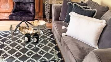 Una sala de estar con sofá, alfombra estampada, mueble de madera y chimenea.