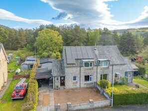 A stone house with a sloped roof, a garage, and a paved driveway. - Cannich Cottage by Interhome (Cannich)