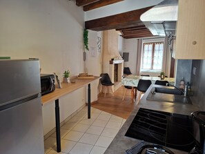 Eine kleine Küche mit Kühlschrank, Mikrowelle und Herd. Ein Essbereich mit Stühlen und Tisch ist ebenfalls vorhanden.