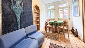Una habitació amb un sofà blau, una taula amb caires, una prestatgeria i un quadre abstracte de grans dimensions a la paret.