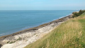 Eine Küstenlandschaft mit felsiger Küste, grünen Wiesen und freiem Blick auf das Meer.