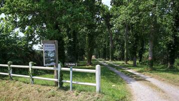 A rural road with a wooden fence and a sign indicating 'La Rochelle' and 'Gîte et Chambres d'hôtes'.