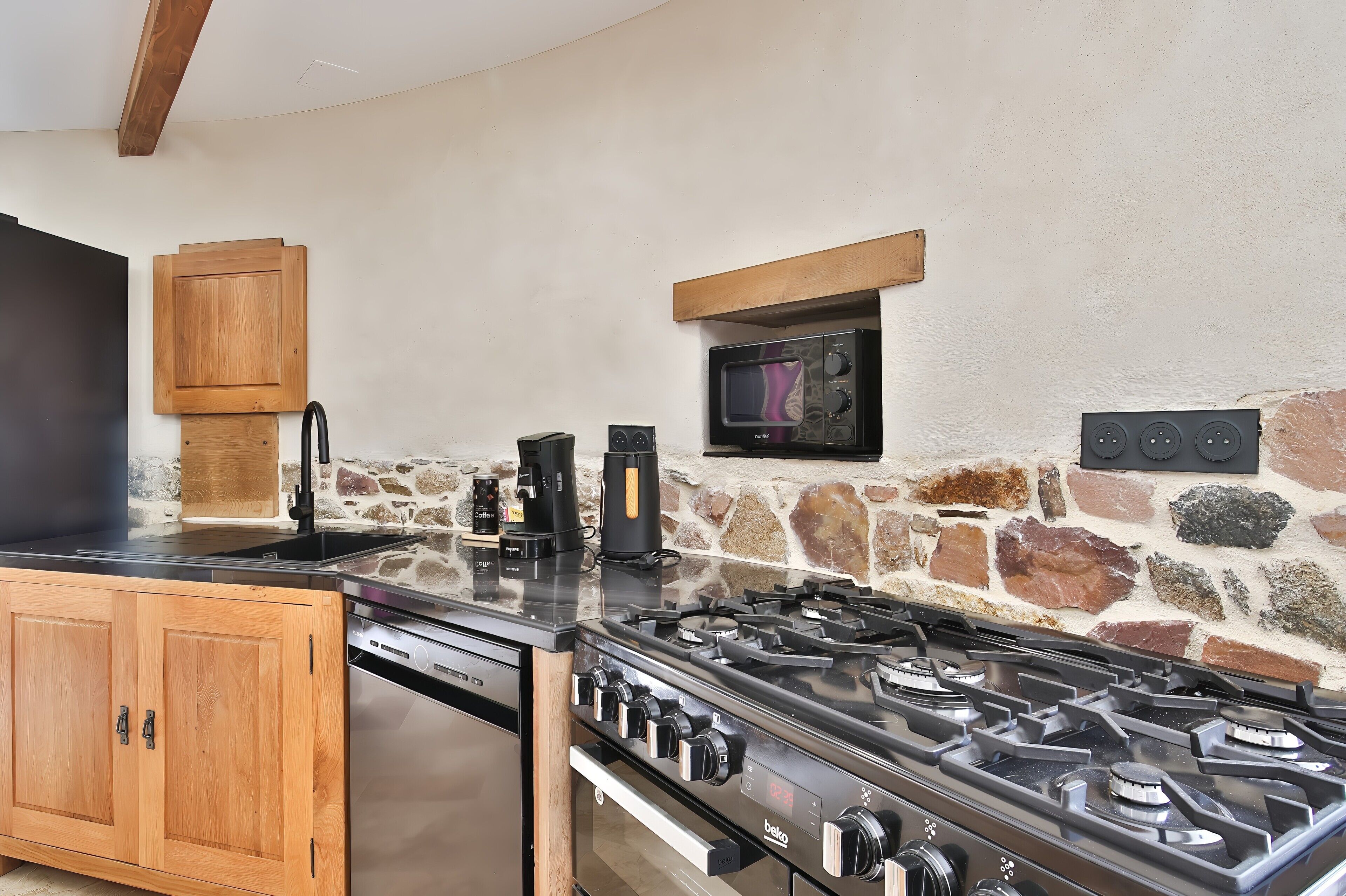 Una cucina con gas, macchina del caffè e forno a microonde.