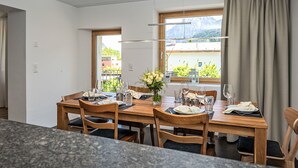 A dining area with a wooden table, chairs, and a view of mountains through the window.