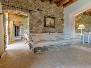 A stone-walled room with a sofa, a painting, and a lamp. - Mas Silvestre by Interhome (La Bisbal D'Emporda)