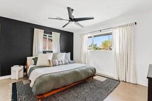 A modern bedroom with a bed, a ceiling fan, a window with curtains, and a view of the outdoors. - The Hideaway at Chandler (Chandler)