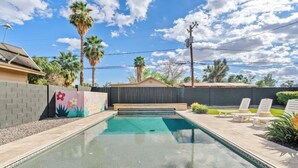 A swimming pool with a wooden deck, lounge chairs, and a colorful mural on the wall. - The Hideaway at Chandler (Chandler)