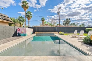 A swimming pool with a wooden deck, lounge chairs, and a colorful mural on the wall. - The Hideaway at Chandler (Chandler)