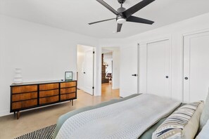 A bedroom with a bed, a dresser, a ceiling fan, and a door leading to another room. - The Hideaway at Chandler (Chandler)