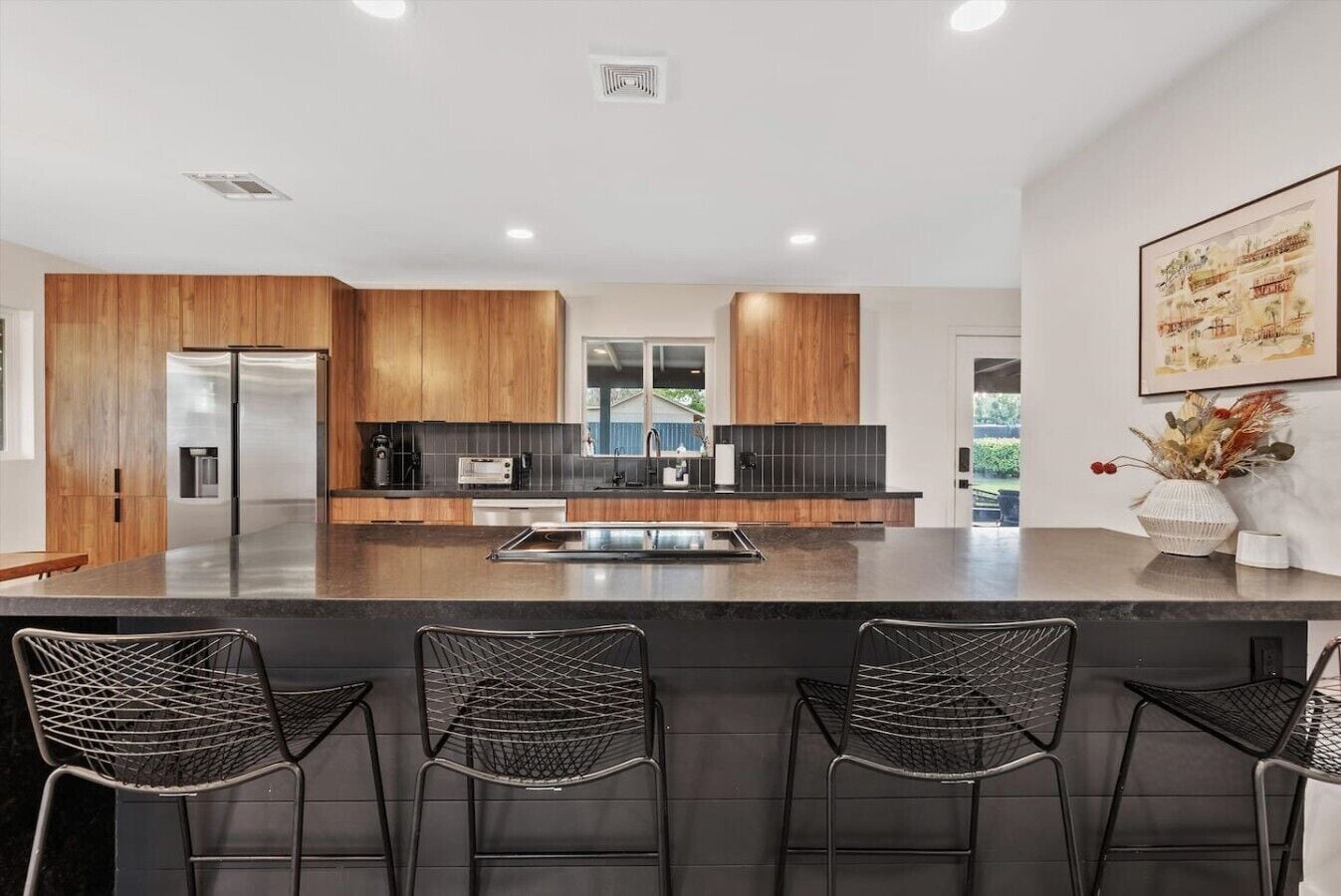 A modern kitchen with wooden cabinets, a central island, and bar seating.