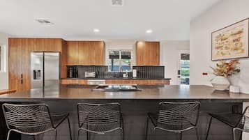 A modern kitchen with wooden cabinets, a central island, and bar seating.