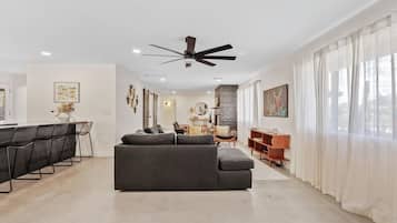 A modern living room with a sofa, dining area, and a ceiling fan.