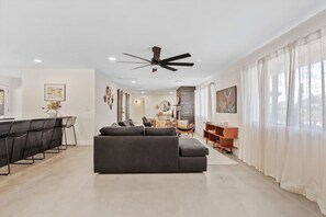 A modern living room with a sofa, dining area, and a ceiling fan. - The Hideaway at Chandler (Chandler)