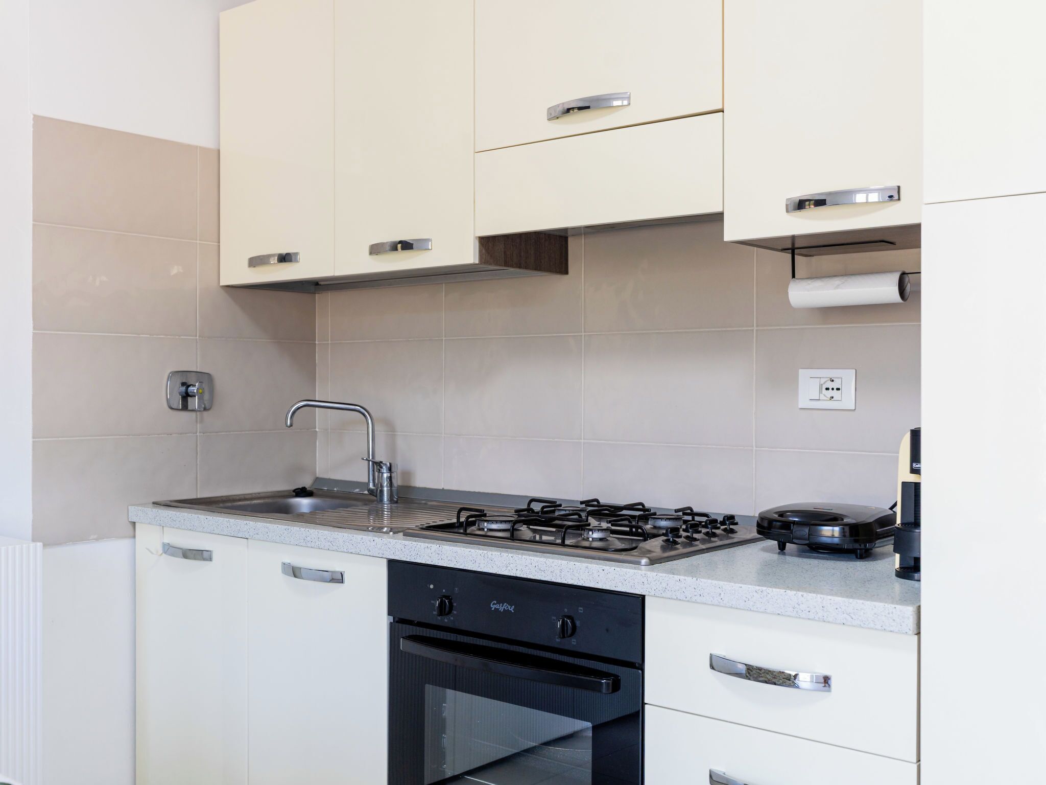 A modern kitchen with white cabinets, a stainless steel sink, and a gas stove.