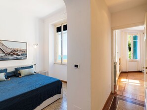 A bedroom with a bed, a window with shutters, a wall-mounted light, and a door leading to another room. - Villa Cristina by Interhome (Imperia)