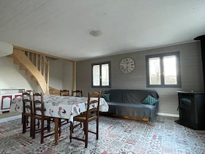 Ein Essbereich mit Tisch und Stühlen, einer Couch, einer Uhr und einer Treppe.