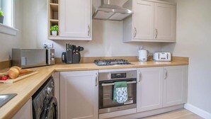 A kitchen with a dishwasher, oven, toaster, and a gas stove. - Mitchell Apartment - 1 Bedroom (North Lanarkshire)