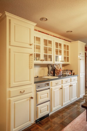 A kitchen with white cabinetry, a built-in oven, and a countertop with a coffee maker.