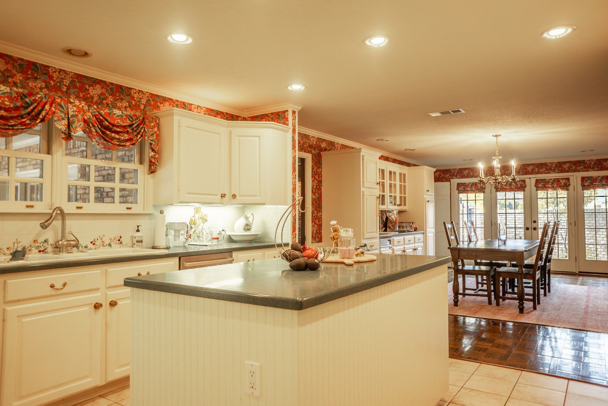 A kitchen with a central island, white cabinetry, and a dining area with a table and chairs.