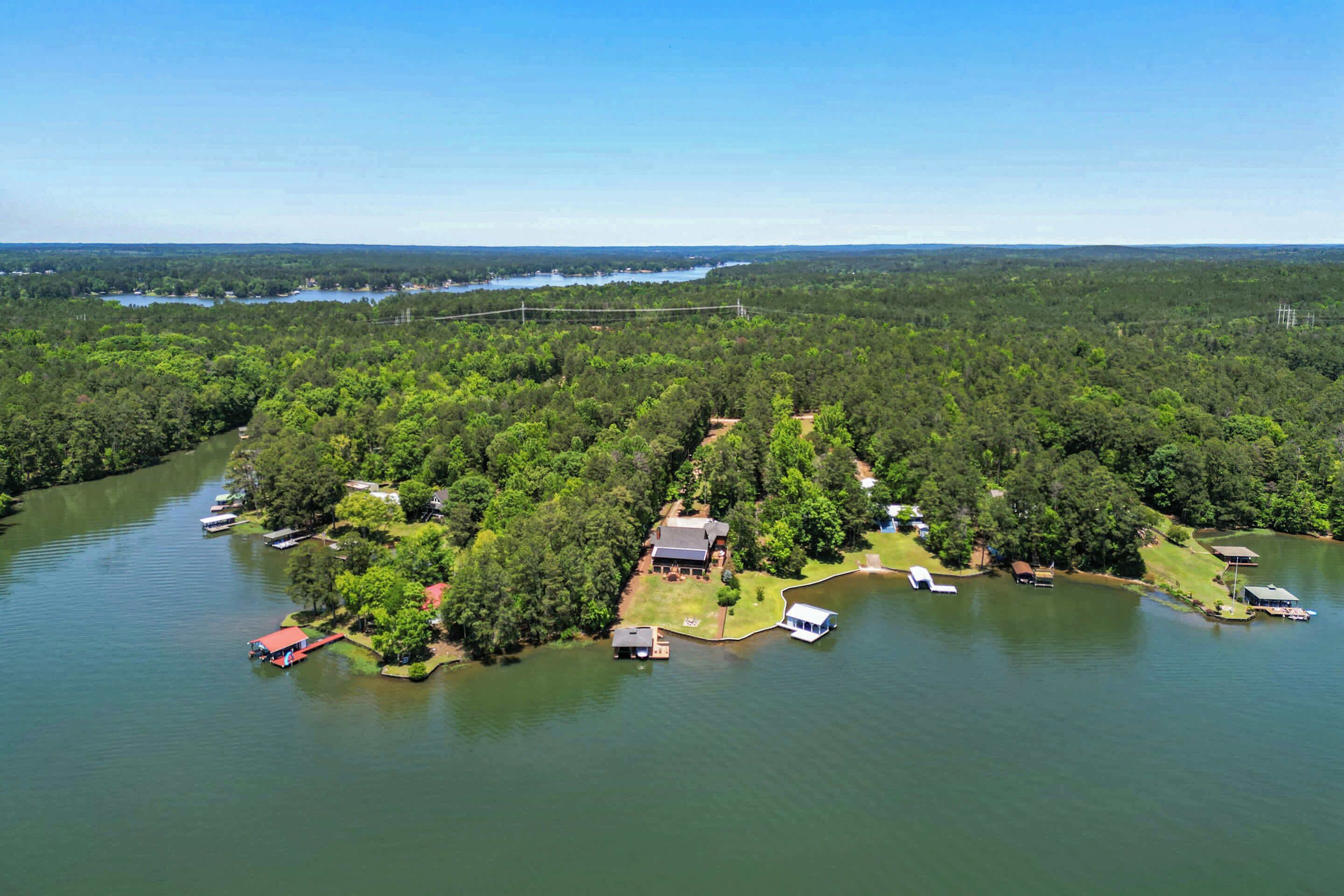 An aerial view of a lakeside property with a house, dock, and boats.