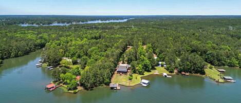 An aerial view of a lakeside property with a house, dock, and boats.